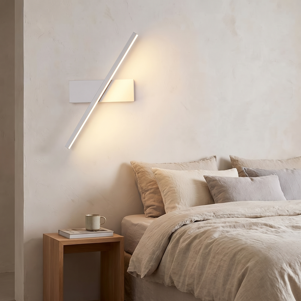 Modern wall sconce mounted beside a bed in a calm bedroom