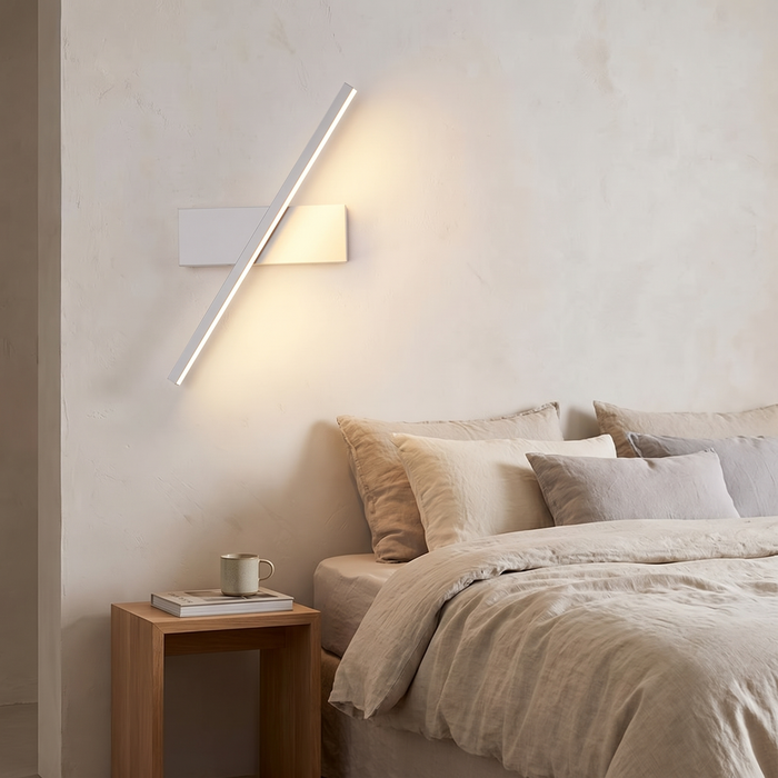 Modern wall sconce mounted beside a bed in a calm bedroom