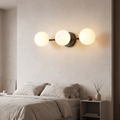 Triple globe LED wall light in a modern bedroom