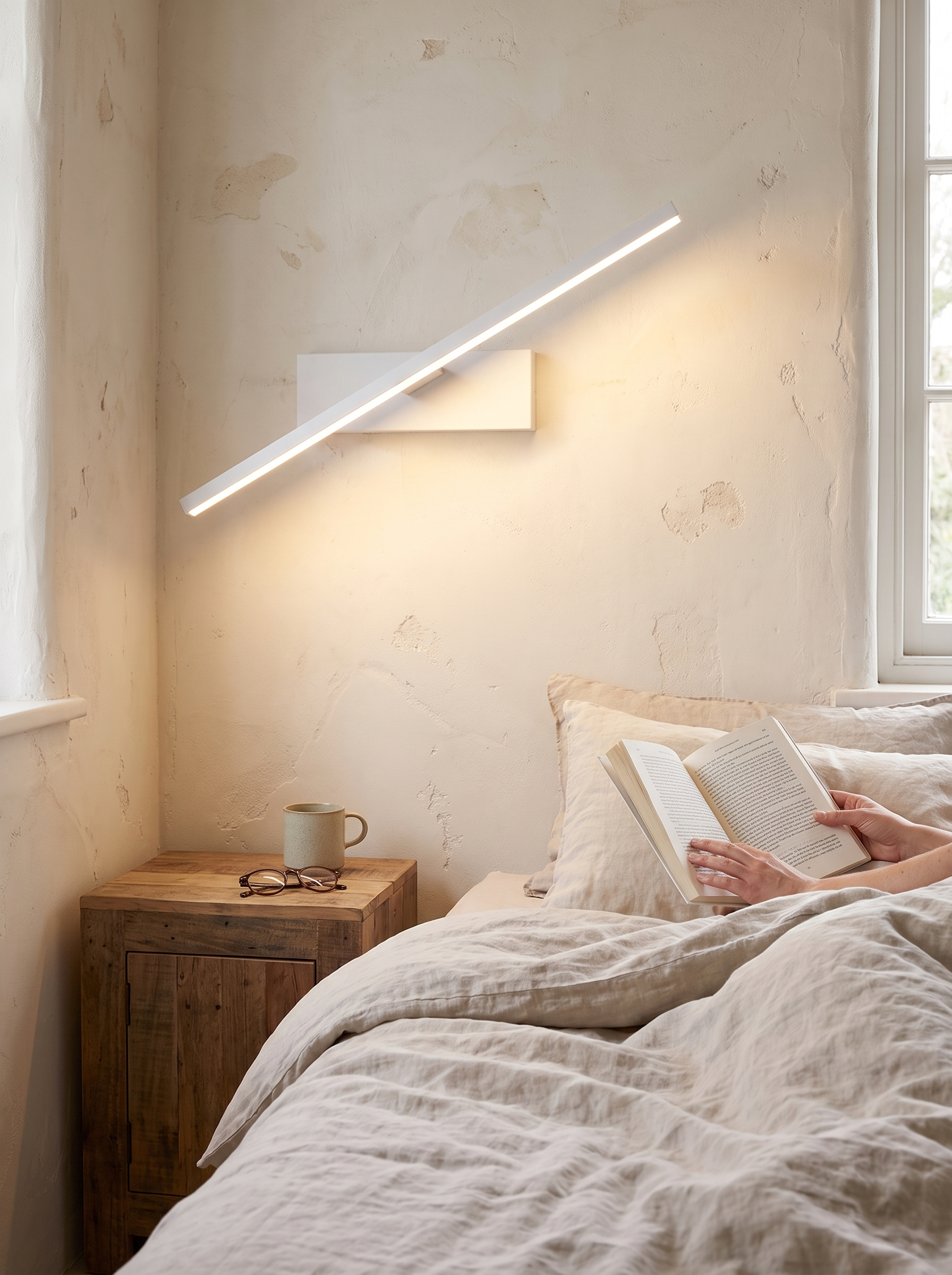 Rotatable LED wall sconce angled beside a bed for reading